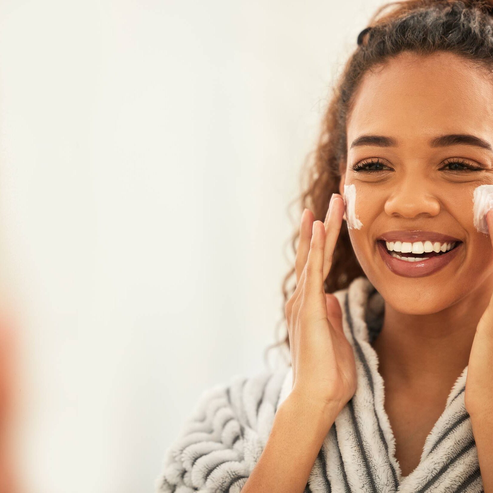 GettyImages-1369183575 A woman is putting lotion on her face.